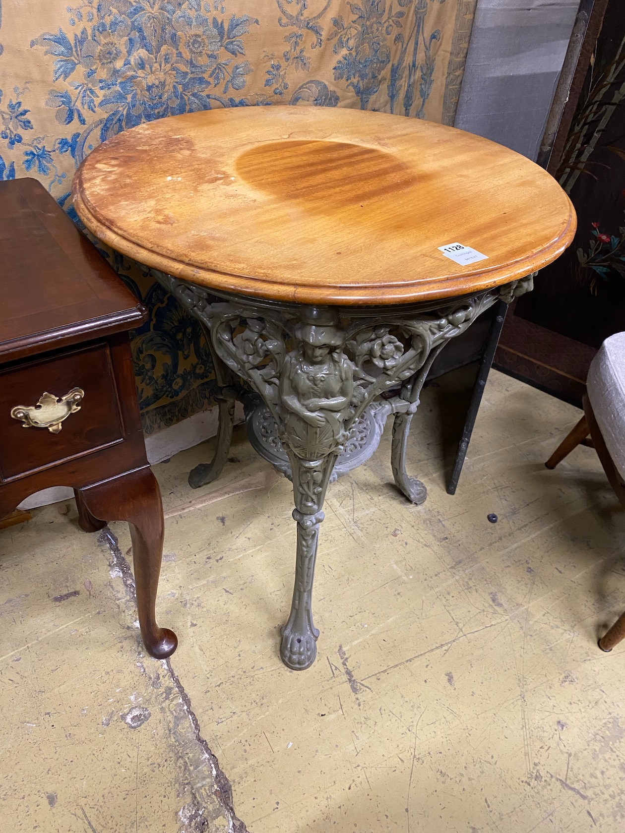 A painted cast iron Britannia pub table with circular mahogany top, diameter 68cm, height 76cm